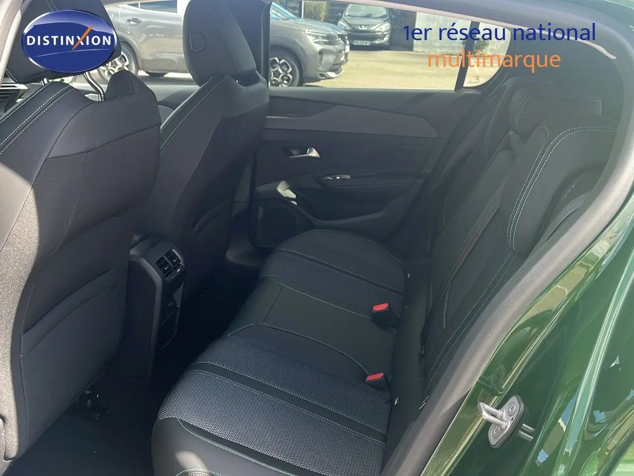 Vue côté droit arrière sur l'intérieur noir avec surpiqûres vertes d'une Peugeot 308 1.2 Hybrid 136ch finition Allure vert olivine métal.