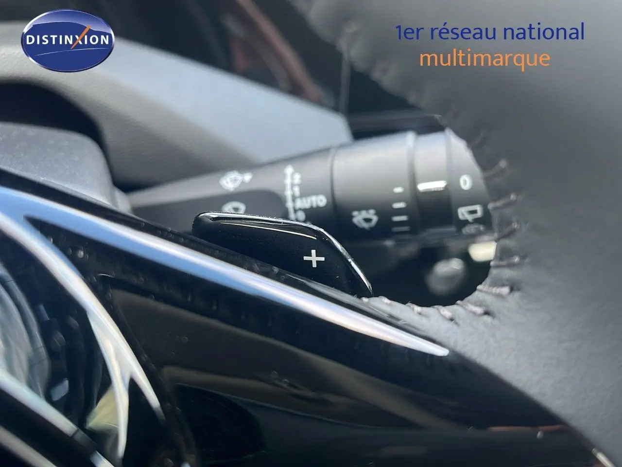 Gros plan sur la palette de changement de vitesse "+" derrière le volant en cuir d'une Peugeot 308 hybride 2024.