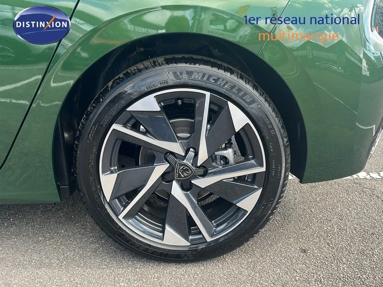 Gros plan sur la roue avant droite d'une Peugeot 308 2024 vert olivine métal avec jante alliage bicolore moderne.