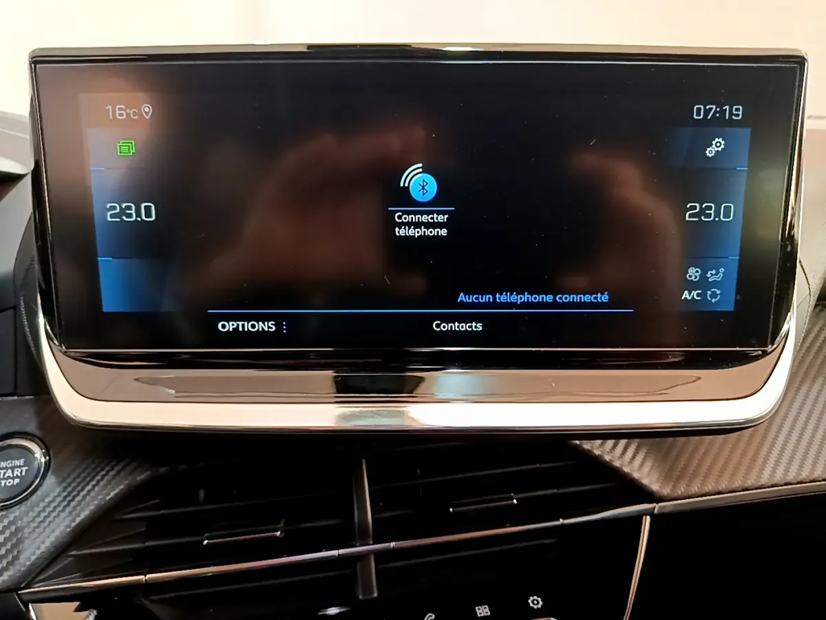 Écran tactile central du tableau de bord du Peugeot 2008 gris clair, affichant la connexion Bluetooth et la climatisation à 23°C.