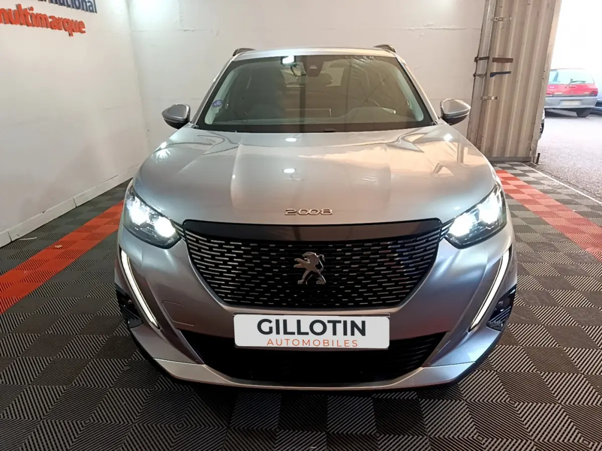 Vue frontale d'un Peugeot 2008 gris clair avec phares allumés et calandre noire distinctive.