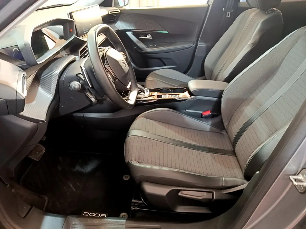 Intérieur avant droit du Peugeot 2008 gris clair 2021, sièges tissu avec surpiqûres et tableau de bord moderne.