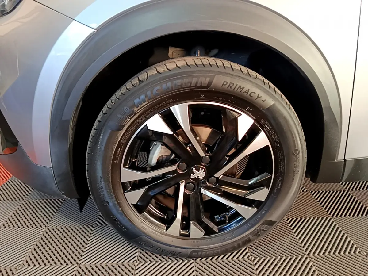 Gros plan sur la roue avant gauche gris clair du Peugeot 2008 avec jante noire et détails Michelin Primacy 4.