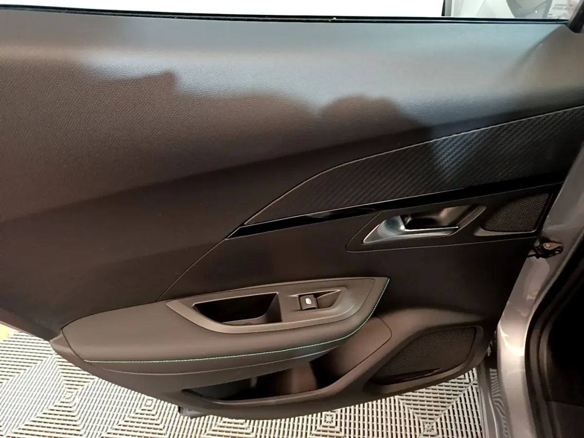 Vue rapprochée de la porte côté gauche gris clair du Peugeot 2008 avec garniture noire et poignée métallique.