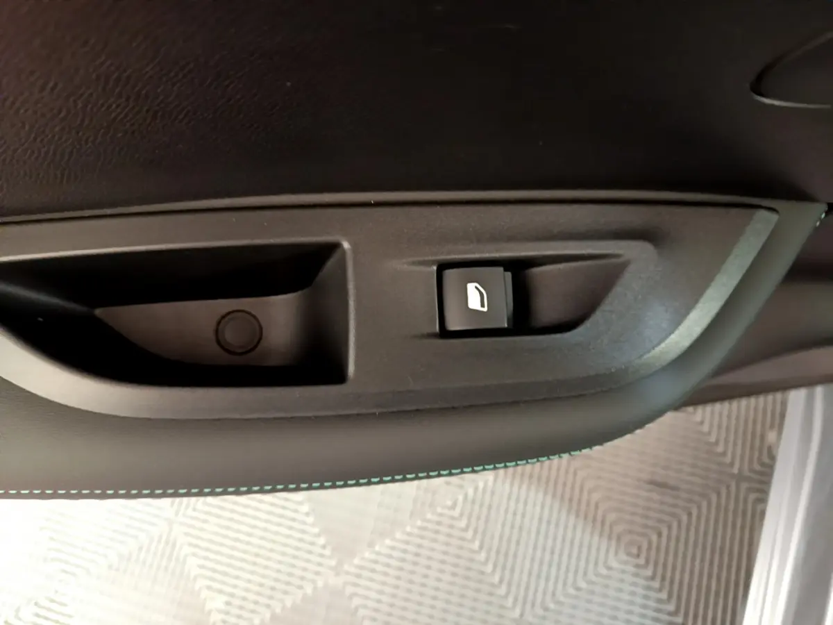 Bouton de déverrouillage de trappe à carburant sur la porte intérieure côté gauche d'un Peugeot 2008 gris clair.