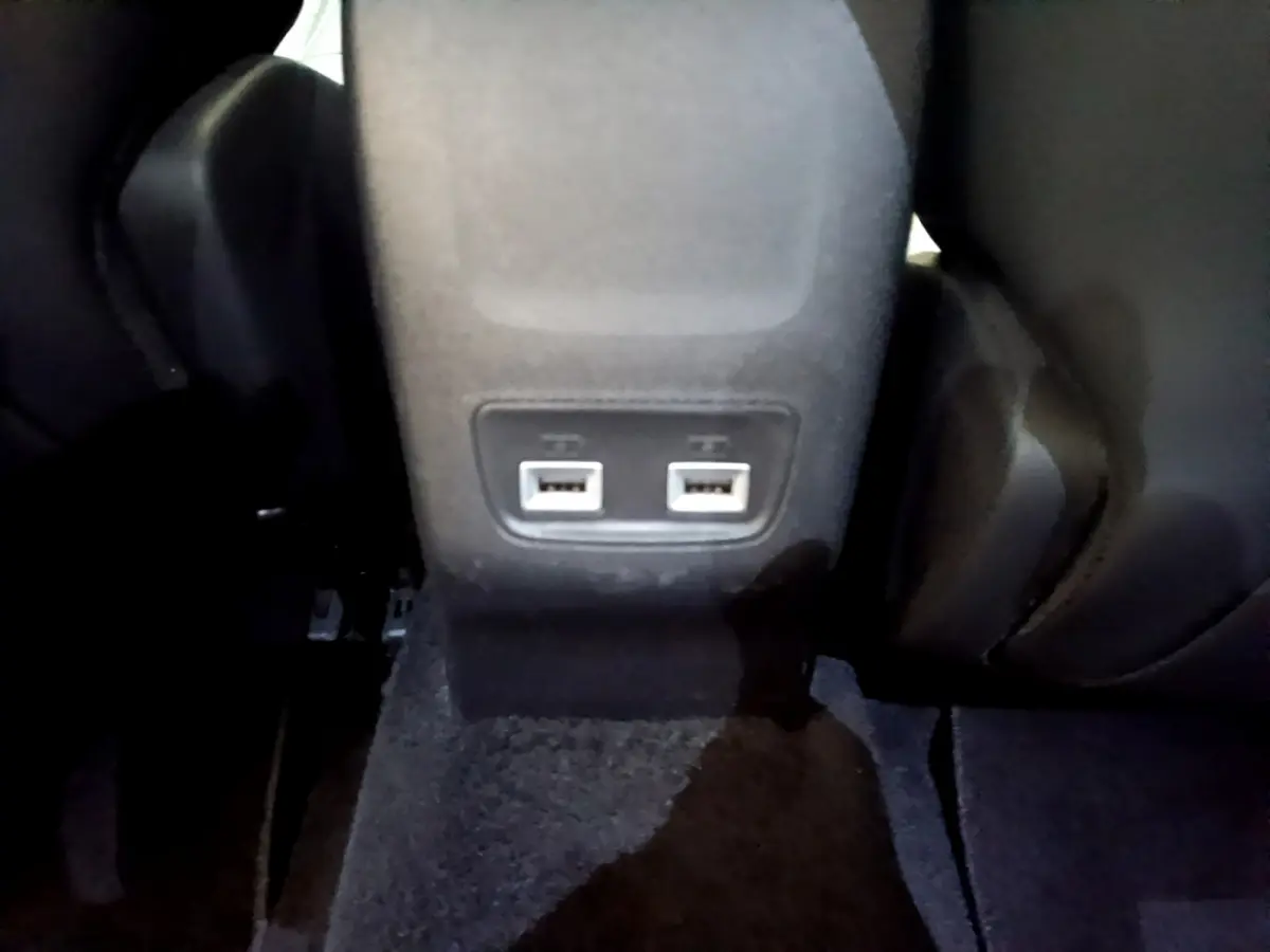 Prise double USB arrière sous les sièges noirs du Peugeot 2008 gris clair, vue rapprochée du plancher.