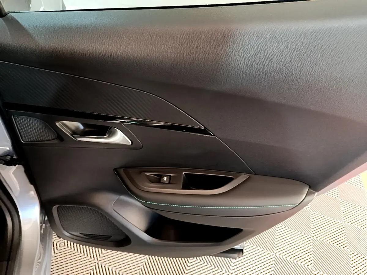 Vue intérieure côté gauche de la porte avant grise claire du Peugeot 2008 avec garniture noire et surpiqûres bleues.