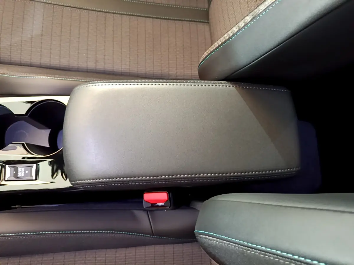 Vue rapprochée de l'accoudoir central gris foncé et des sièges avec surpiqûres bleues dans le Peugeot 2008 2021.