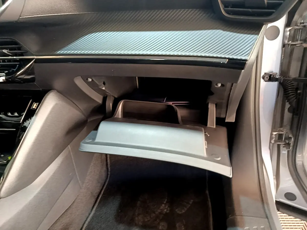 Vue intérieure côté passager du Peugeot 2008 gris clair 2021 avec boîte à gants ouverte et tableau de bord noir.