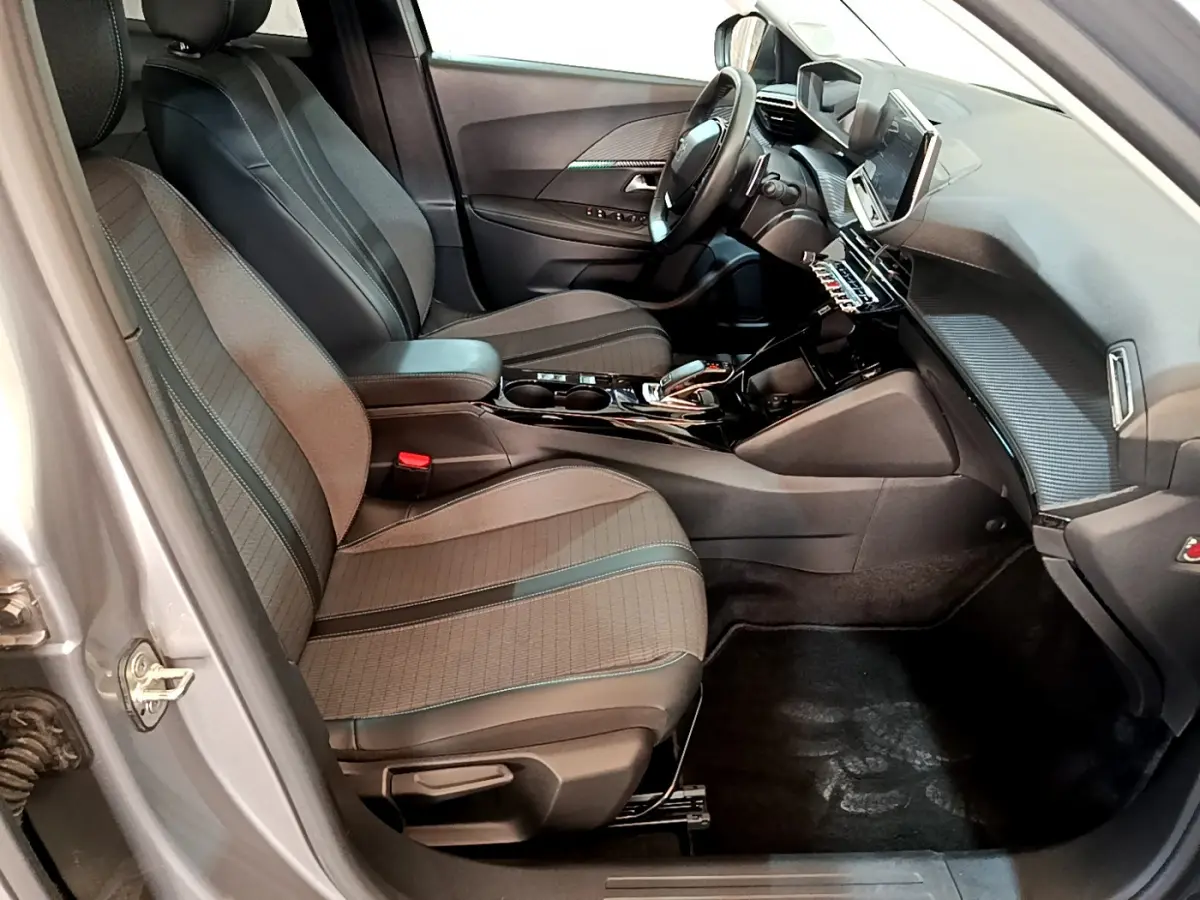Intérieur avant droit du Peugeot 2008 gris clair, sièges tissu avec surpiqûres et tableau de bord moderne tactile.