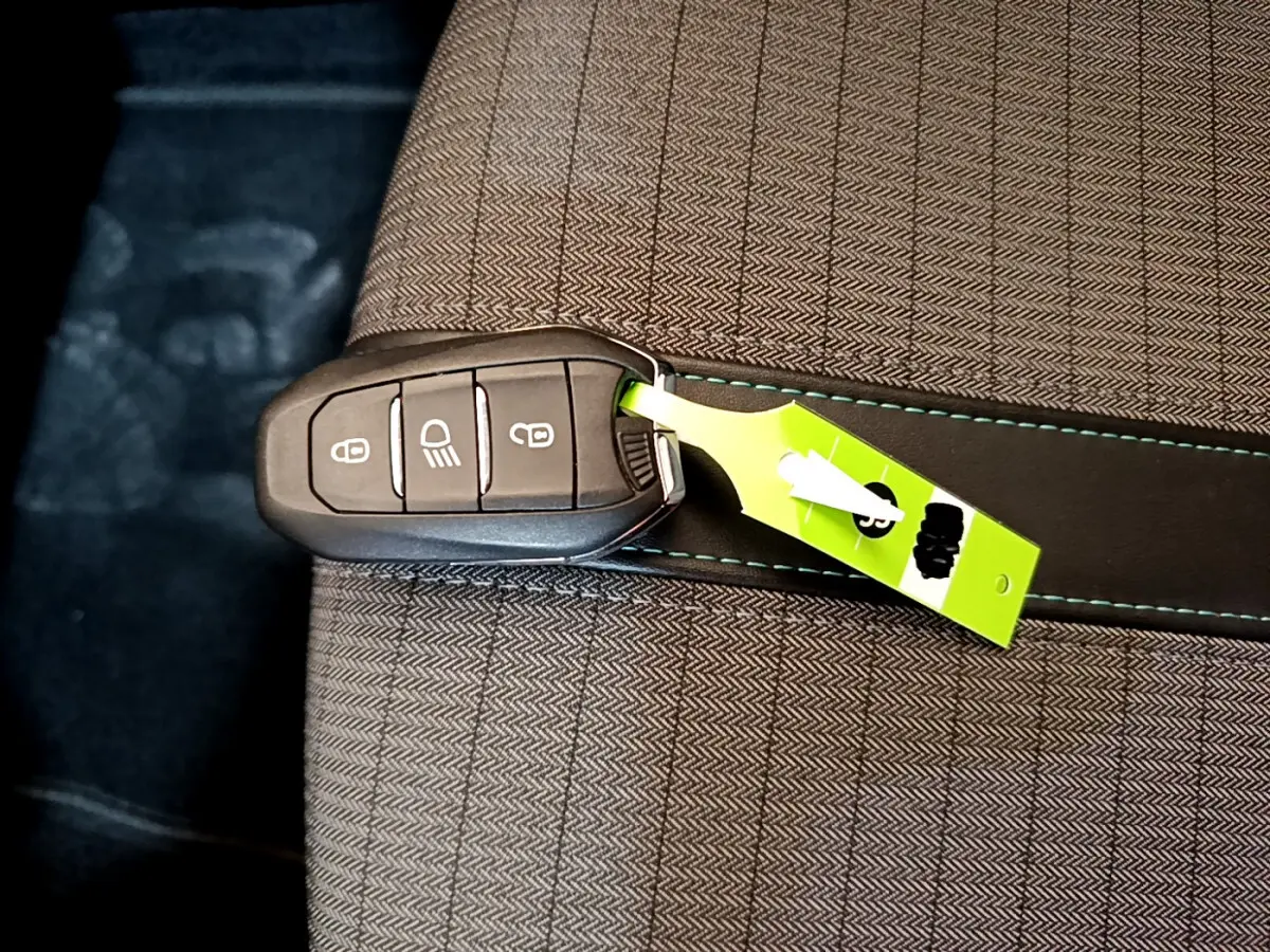 Clé de démarrage noire posée sur un siège tissu gris clair avec surpiqûres bleues du Peugeot 2008 2021.