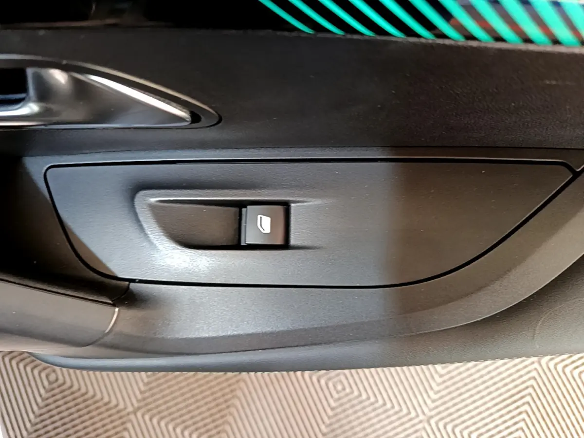 Bouton de commande de lève-vitre sur la portière intérieure noire d'une Peugeot 2008 gris clair, vue rapprochée.