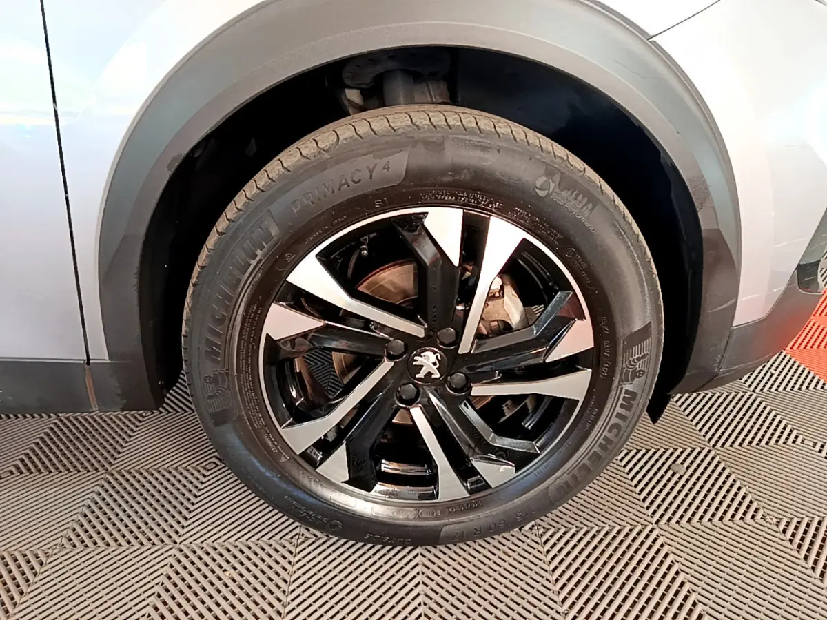 Gros plan sur la roue avant gauche gris clair du Peugeot 2008 avec jante alliage noire et argentée au design moderne.