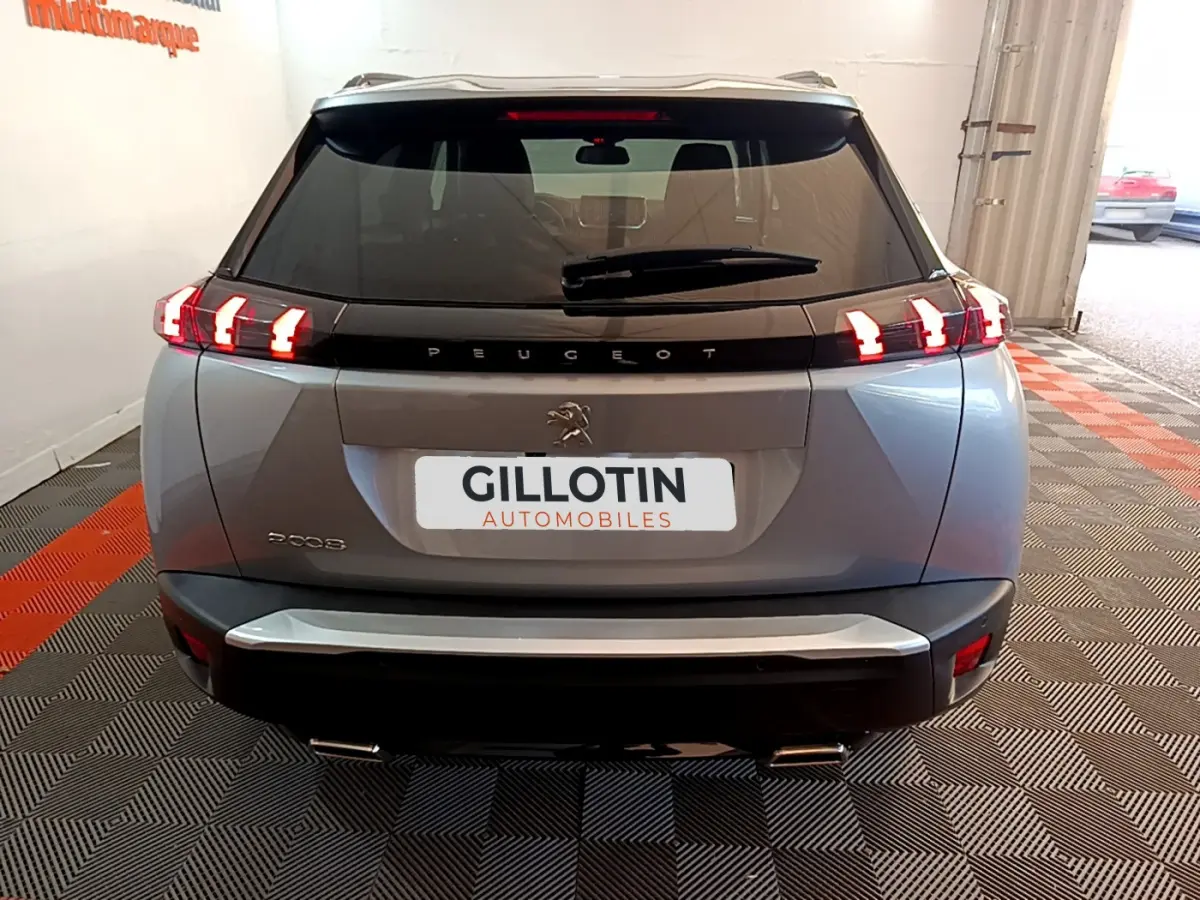 Vue arrière d'un Peugeot 2008 gris clair avec feux LED caractéristiques et double sortie d'échappement visible.