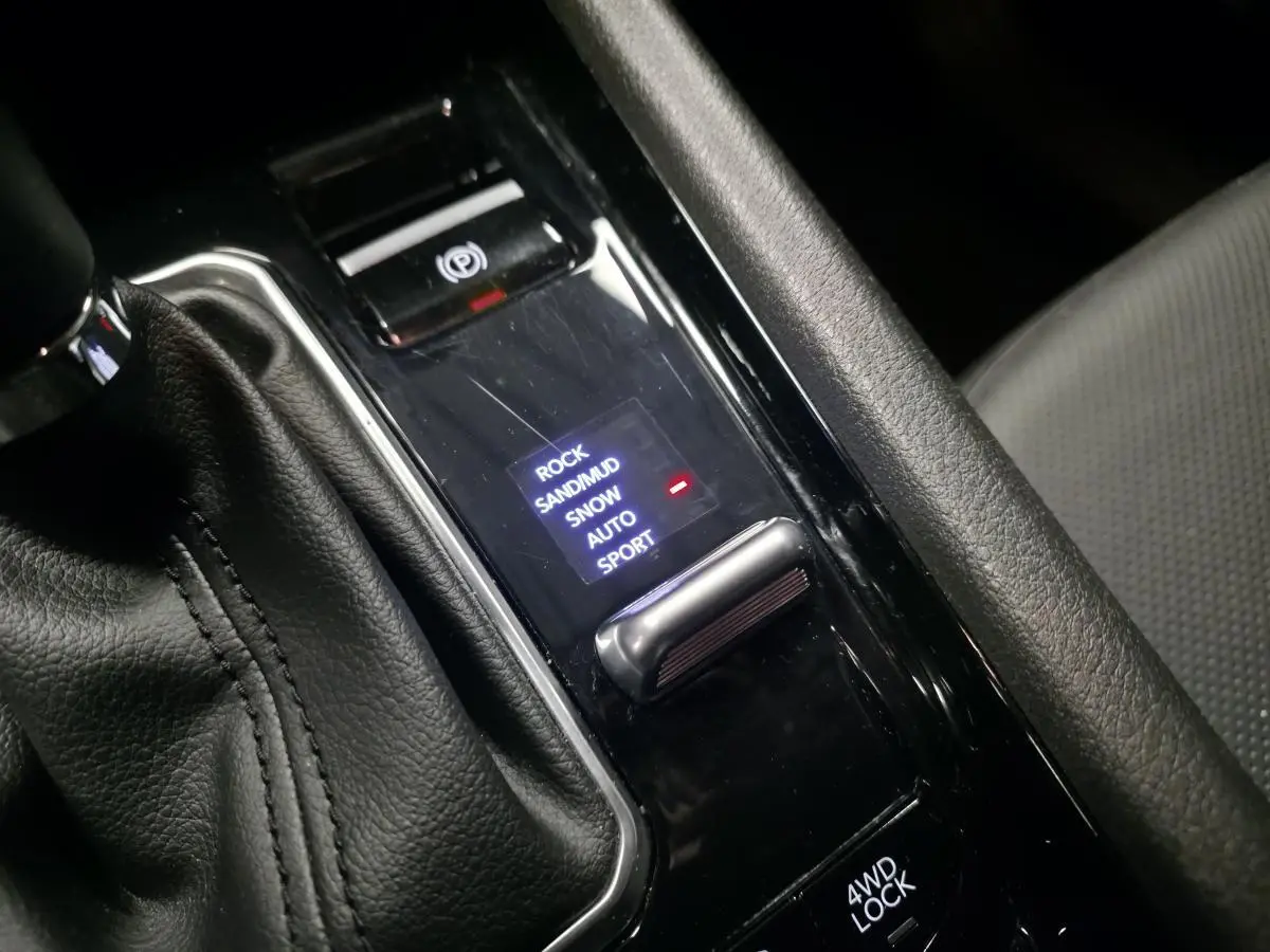 Gros plan sur la console centrale noire du Jeep Compass 2024, montrant la sélection des modes tout-terrain et frein de stationnement électrique.