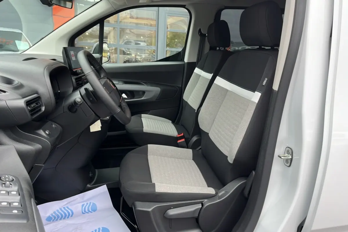 Vue intérieure côté conducteur du Citroën Berlingo Kaolin white 2026, montrant les sièges avant bicolores et le volant multifonctions.