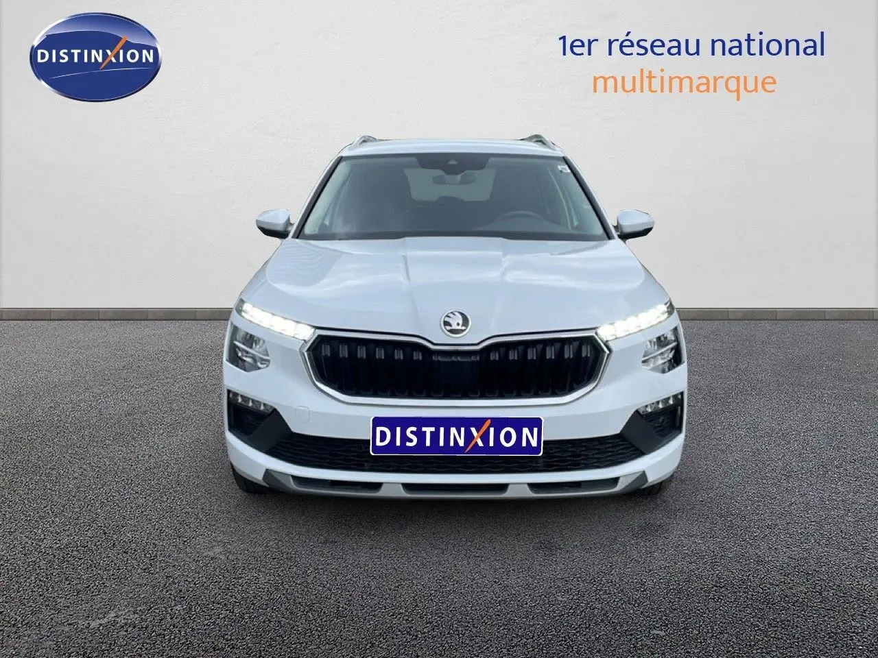 Vue frontale d’un Skoda Kamiq blanc glacier 2025 avec calandre noire et feux LED allumés.
