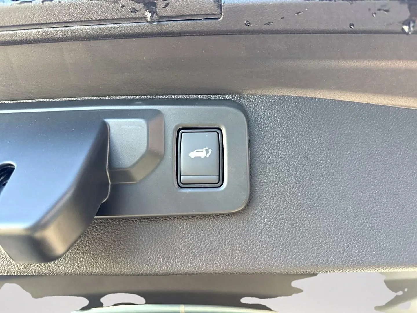 Bouton d'ouverture électrique du coffre sur le panneau intérieur d'une Renault Symbioz gris rafale.