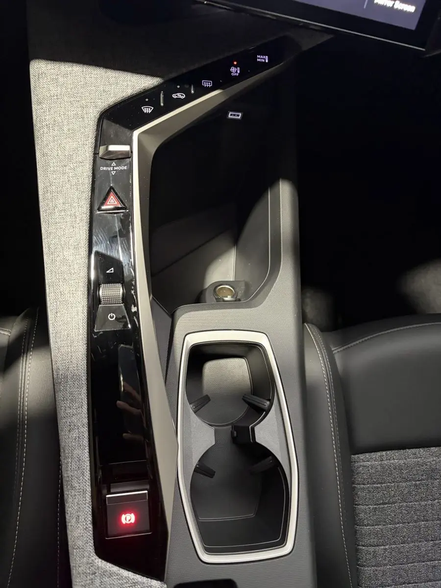 Vue plongeante sur la console centrale noire et grise du Peugeot 3008 blanc, avec porte-gobelets et commandes tactiles.