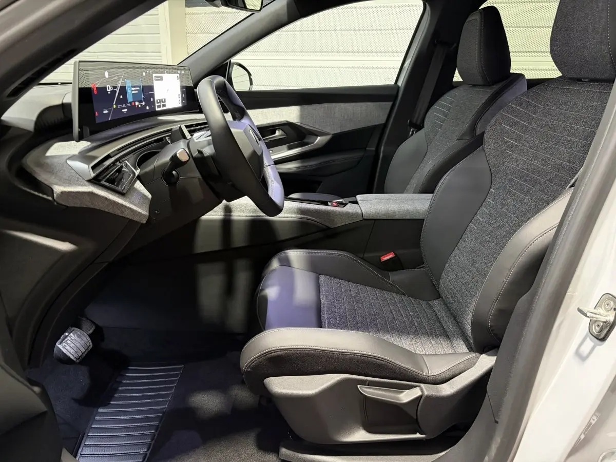 Intérieur côté conducteur du Peugeot 3008 blanc, avec sièges tissu-cuir gris et tableau de bord numérique moderne.