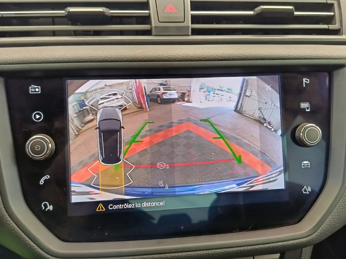 Écran tactile du système de stationnement assisté montrant la vue arrière et latérale d'une SEAT Arona bleue.