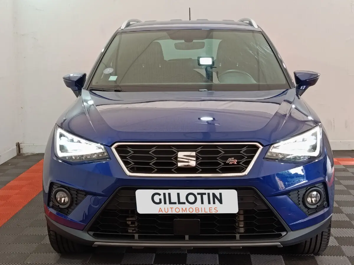Vue frontale d'un SEAT Arona bleu 2021 avec phares LED allumés et logo FR sur la calandre noire.