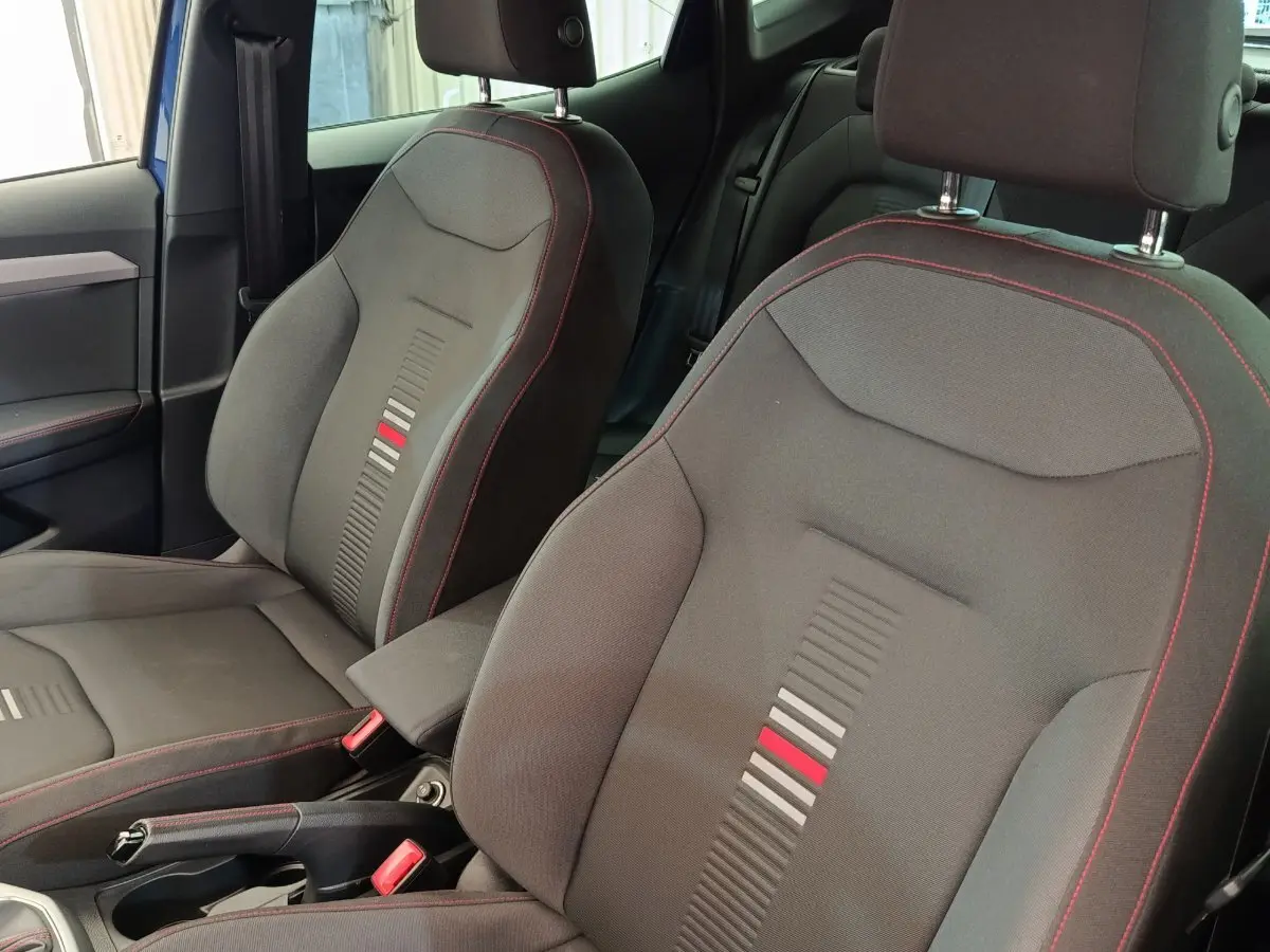 Vue intérieure rapprochée des sièges avant noirs avec surpiqûres rouges du SEAT Arona bleu 2021 finition FR.