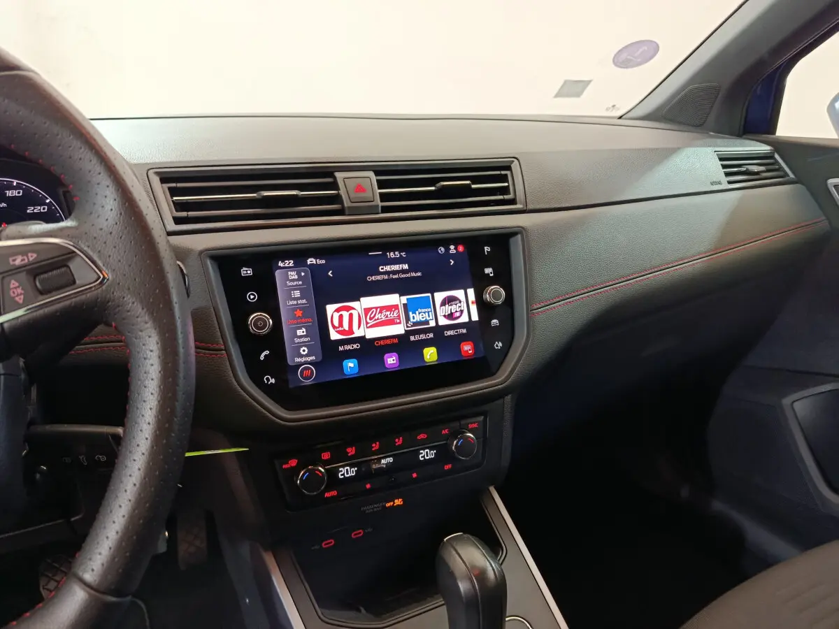 Vue intérieure côté passager du tableau de bord noir avec écran tactile et volant cuir du SEAT Arona bleu 2021.