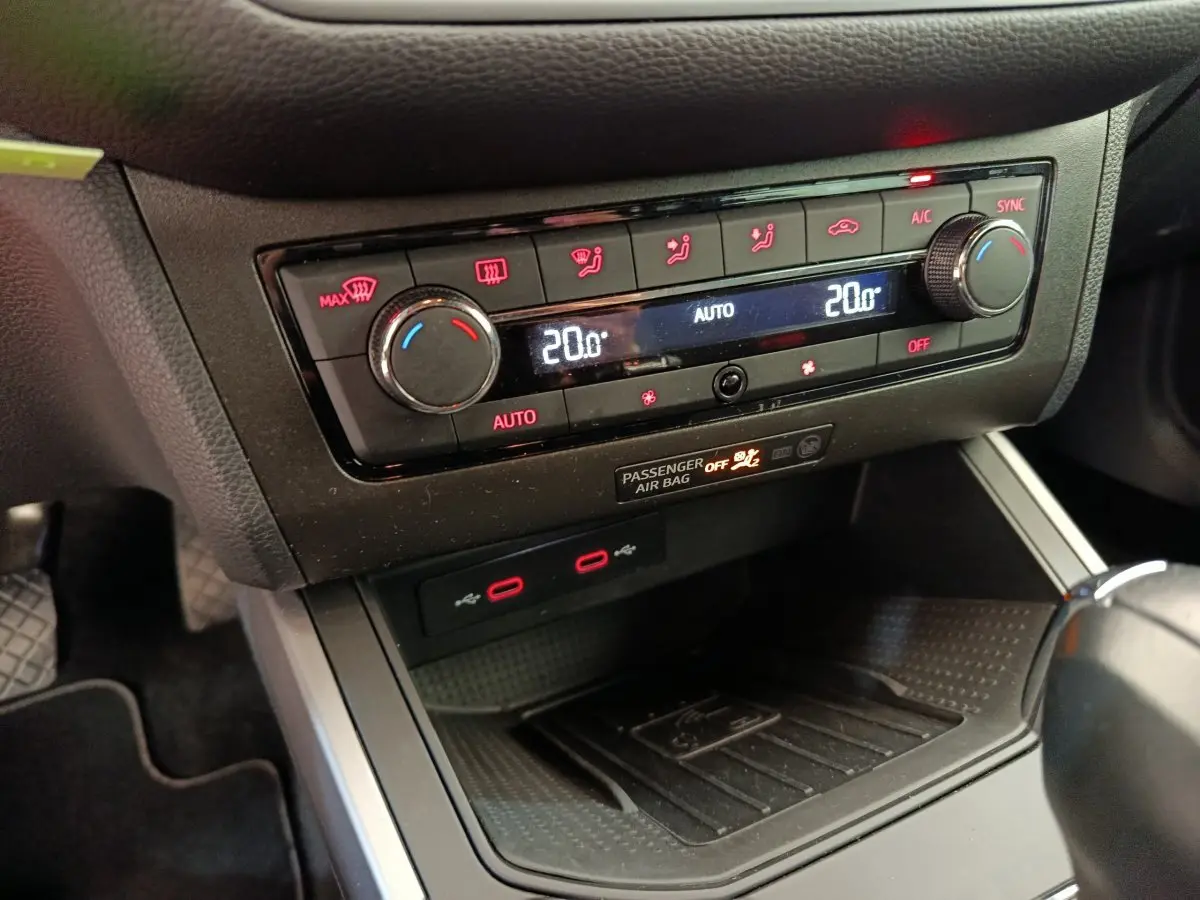 Gros plan sur la console centrale du SEAT Arona 2021, montrant la climatisation digitale et la zone de recharge sans fil.