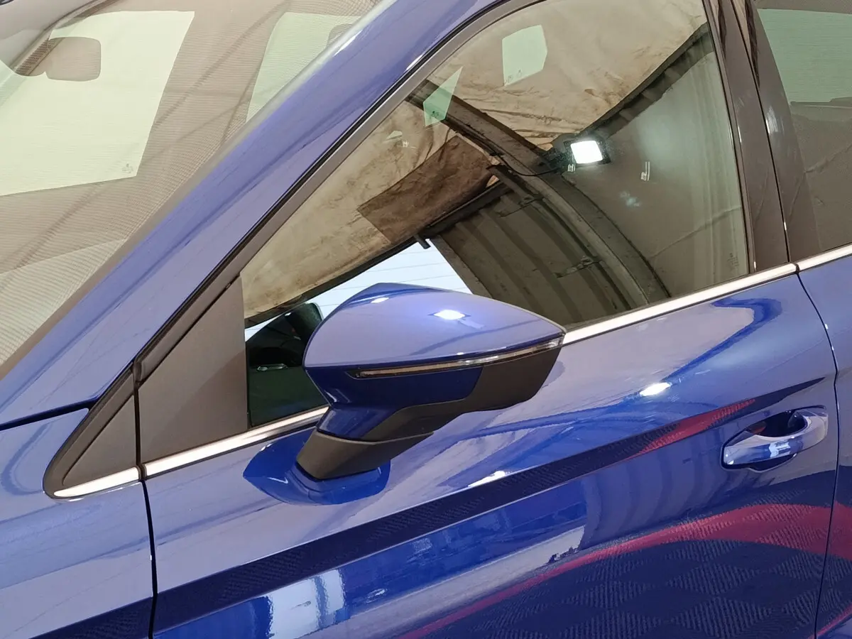 Gros plan sur le rétroviseur côté conducteur bleu d'un SEAT Arona 2021 avec poignée de porte assortie.