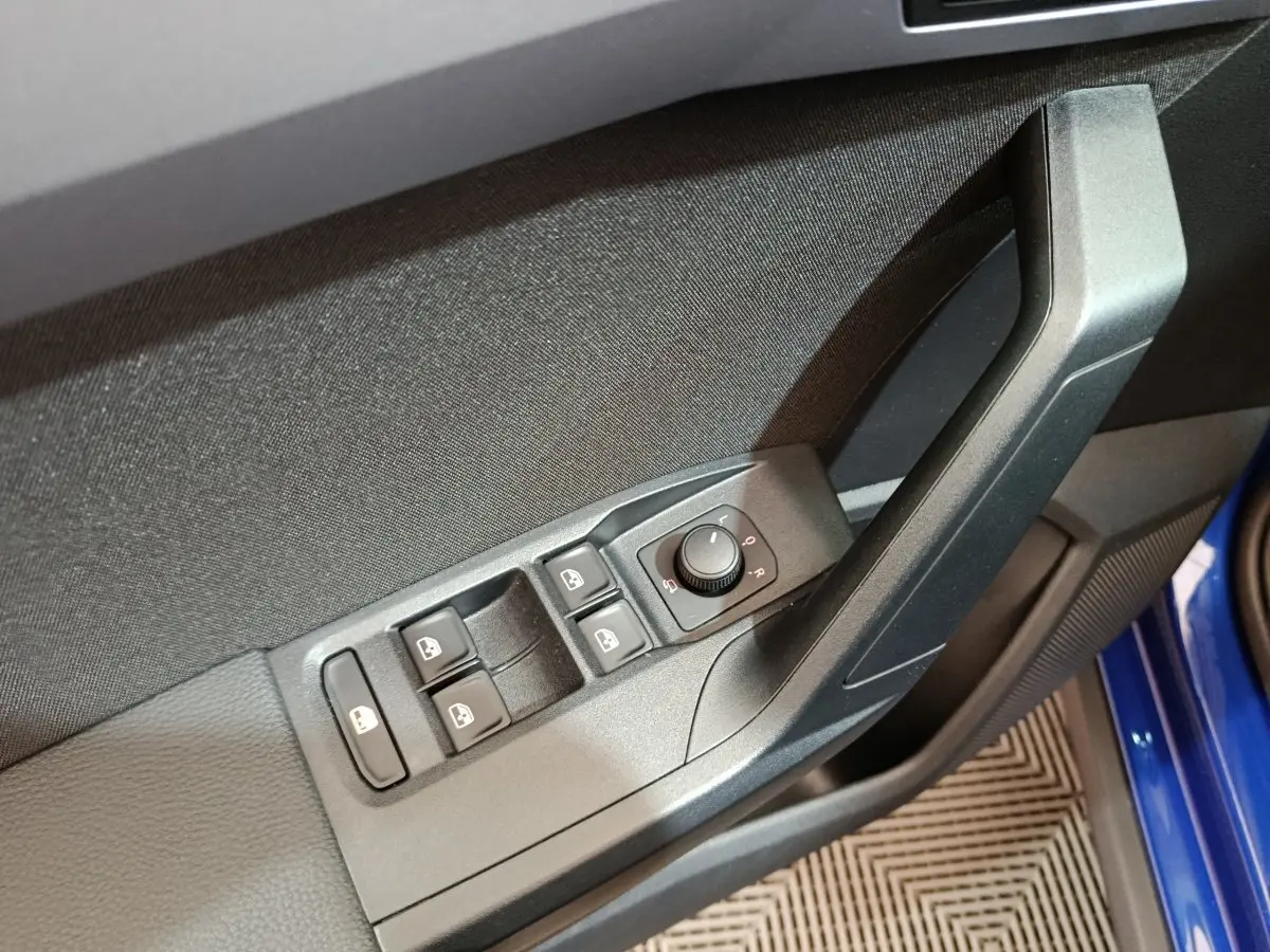 Gros plan sur la commande des vitres et rétroviseurs côté conducteur d'une SEAT Arona bleu 2021.