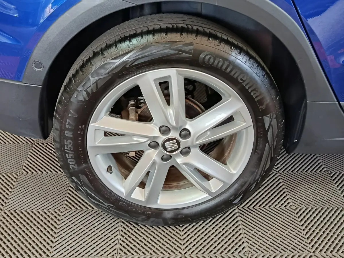 Gros plan sur la roue avant droite d'un SEAT Arona bleu, mettant en valeur la jante alliage et le pneu Continental.