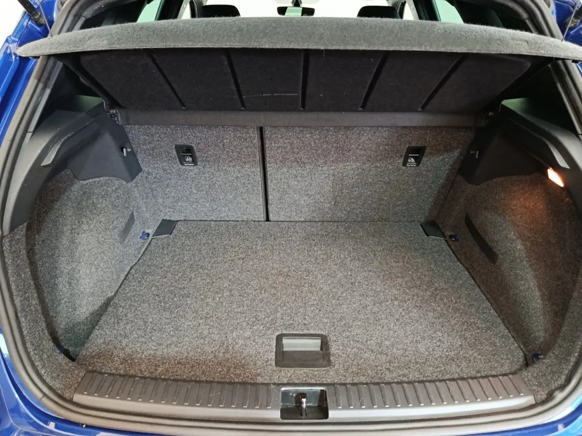 Vue arrière du coffre ouvert du SEAT Arona bleu 2021, montrant l'espace de rangement et la tablette de séparation.