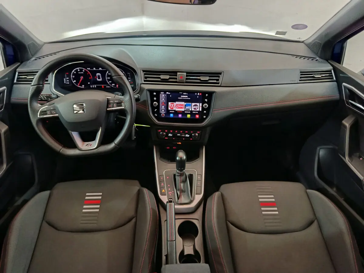 Vue intérieure avant du tableau de bord et des sièges noirs avec surpiqûres rouges du SEAT Arona 2021 finition FR.