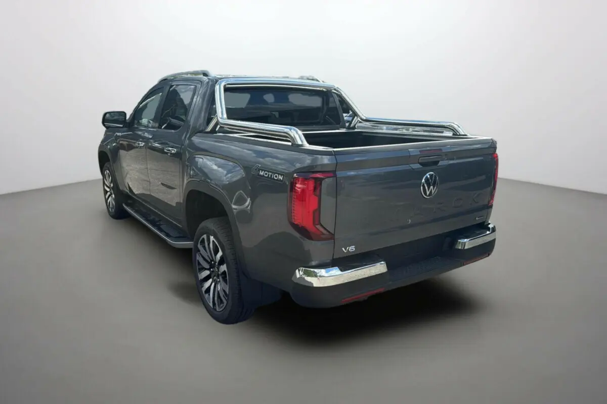 Volkswagen Amarok Simple Cabine V6 240 Aventura gris foncé vu de trois quarts arrière droit avec barres chromées sur la benne.