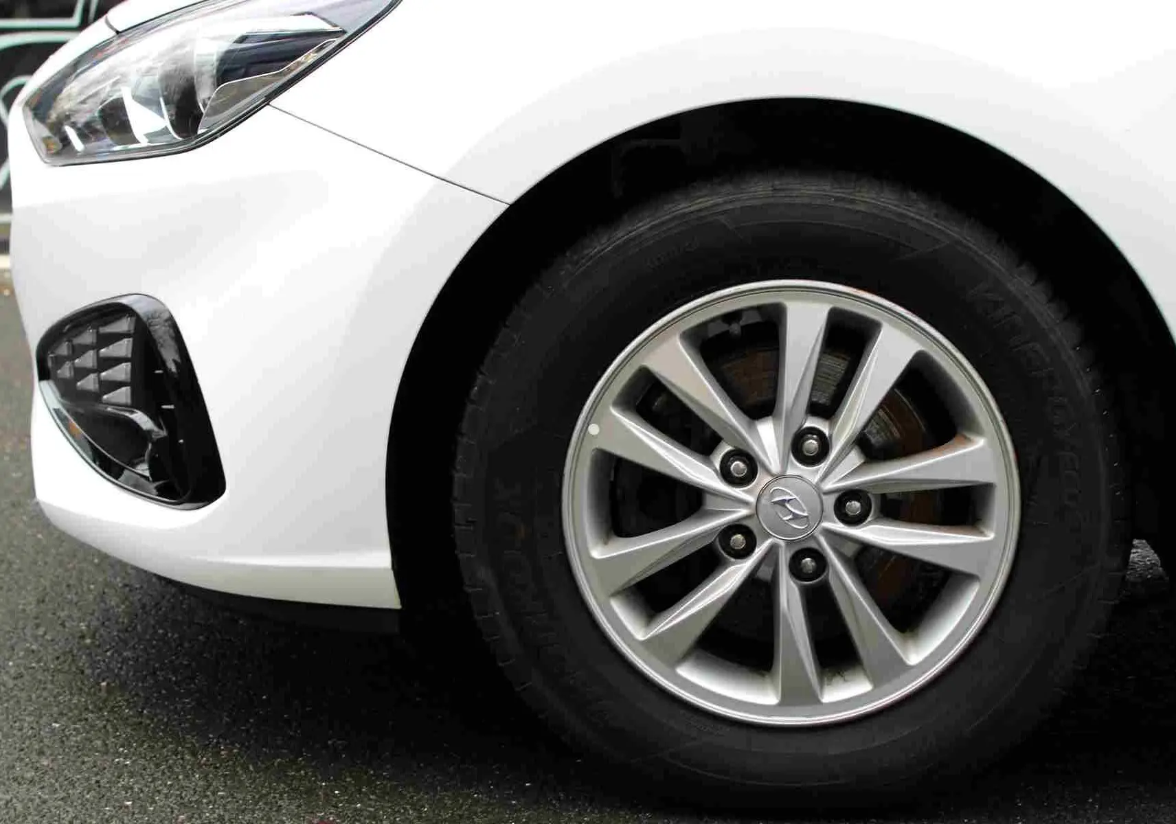 Gros plan sur la roue avant droite et le pare-chocs blanc polaire d'une Hyundai i30 SW 2022 avec jante alliage.