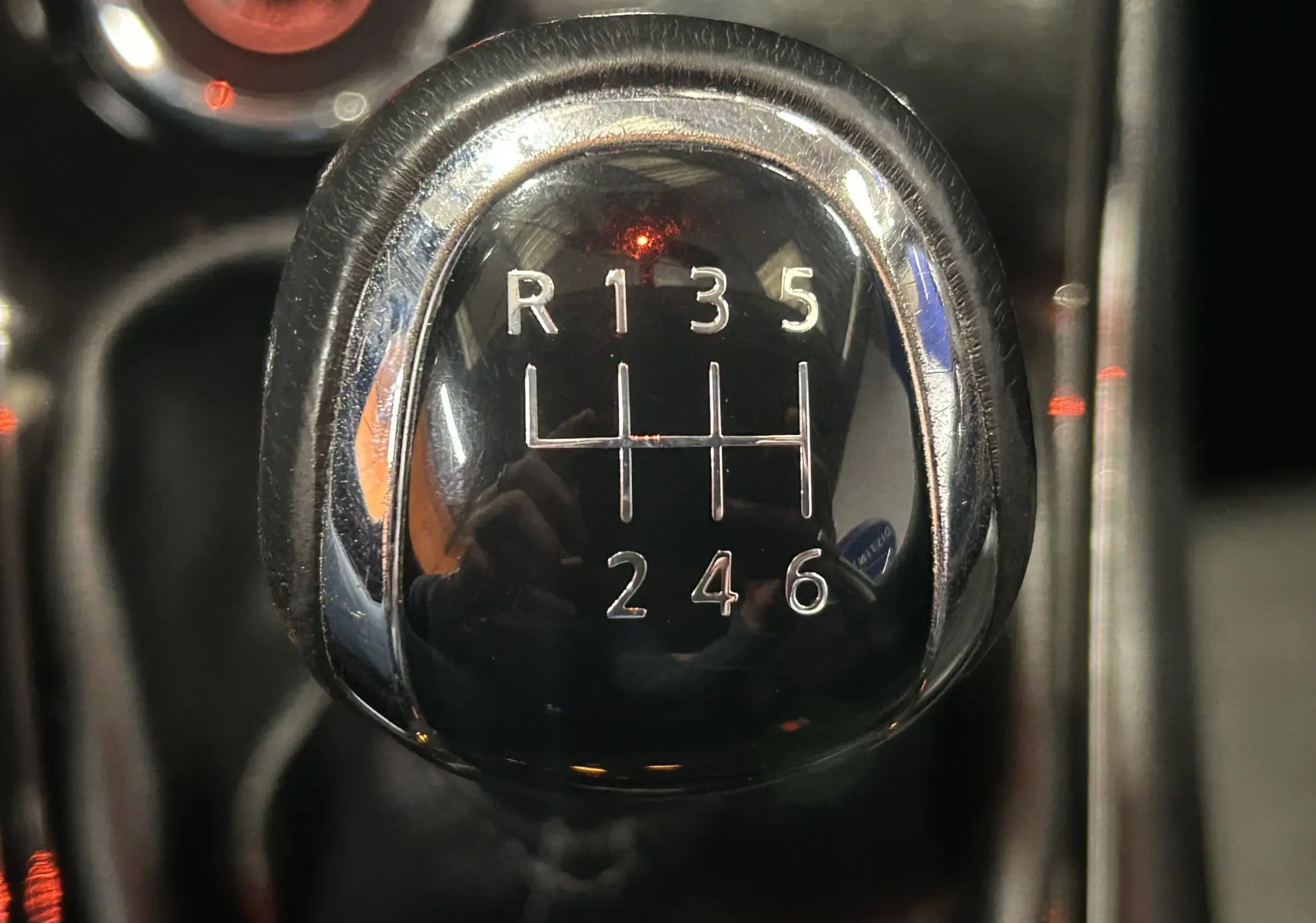 Gros plan sur le pommeau de la boîte manuelle noire de la Nissan Pulsar gris, affichant les six vitesses et la marche arrière.