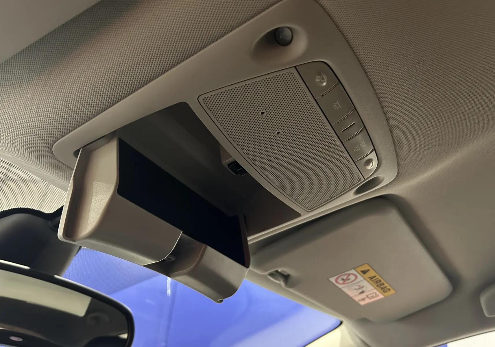 Détail du rangement plafond ouvert et des commandes d’éclairage intérieur dans le toit d’une Nissan Pulsar gris 2018.