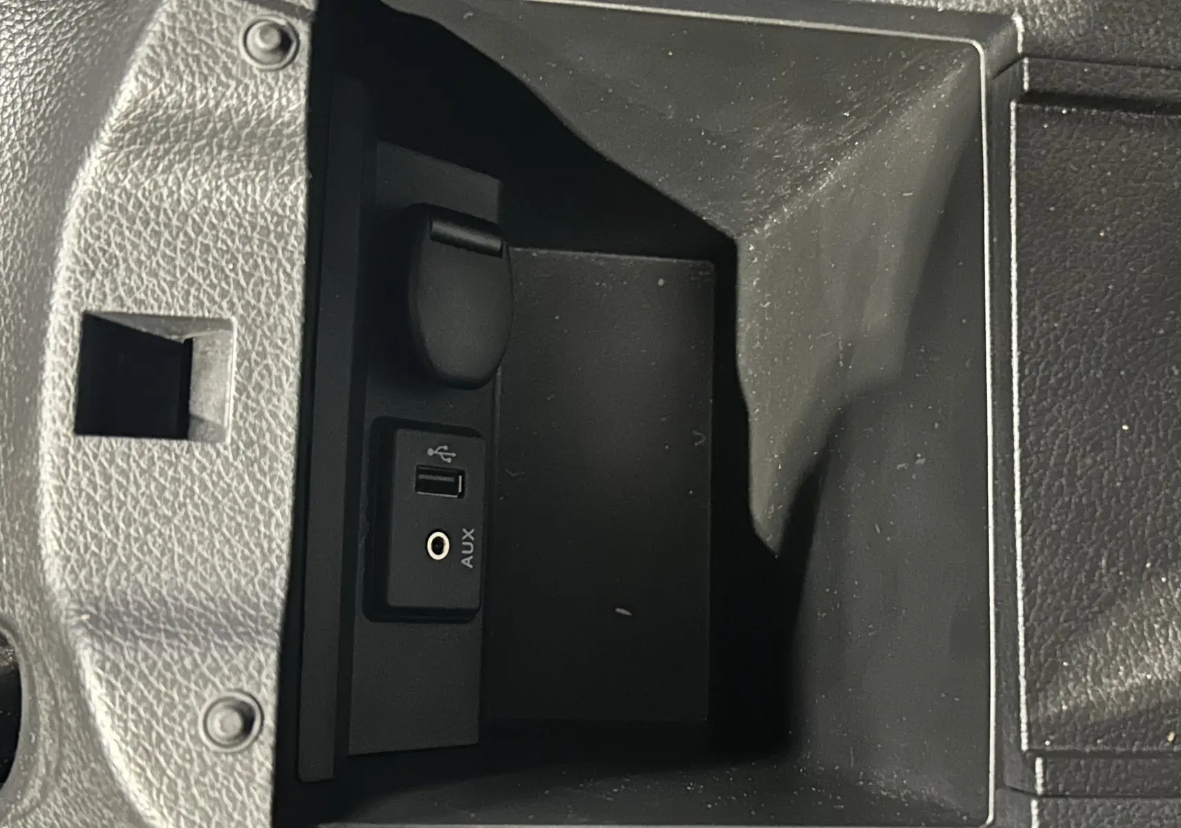 Gros plan sur la prise USB et port AUX dans le rangement central intérieur d'une Nissan Pulsar gris 2018.