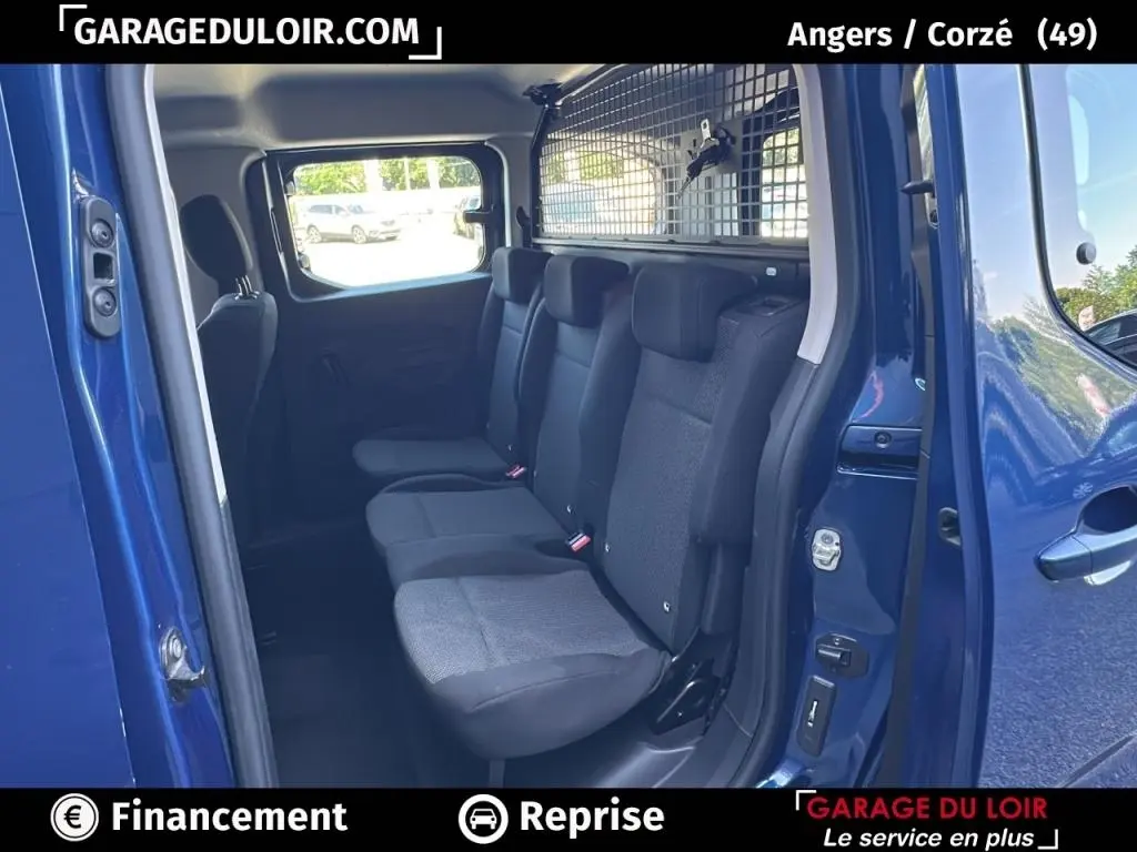 Vue intérieure côté droit du Peugeot Rifter bleu 2024, montrant les sièges arrière et une grille de séparation.