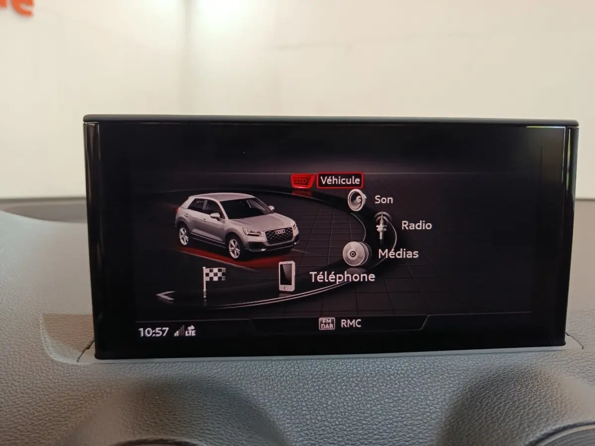 Écran tactile intérieur affichant le menu multimédia avec une Audi Q2 grise vue de profil droit en illustration.