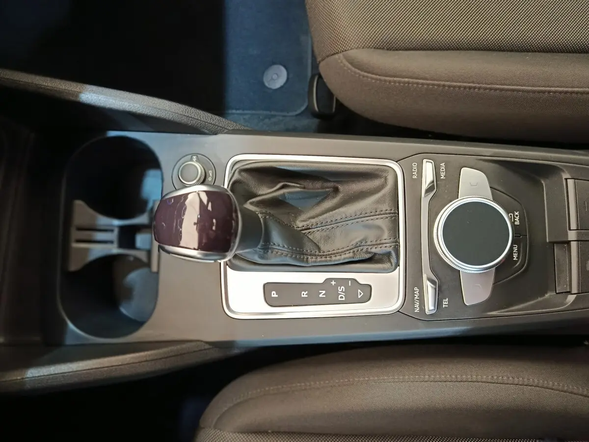 Vue plongeante sur la console centrale de l'Audi Q2 35 TFSI 2022, avec levier de vitesses automatique et molette de contrôle multimédia.