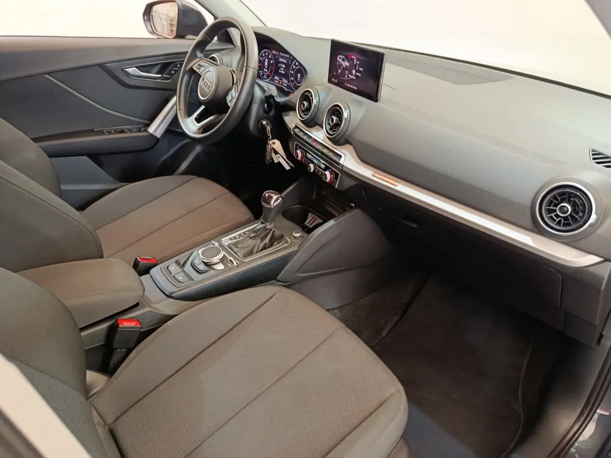 Intérieur avant droit de l'Audi Q2 gris foncé 2022, avec tableau de bord digital et console centrale moderne.