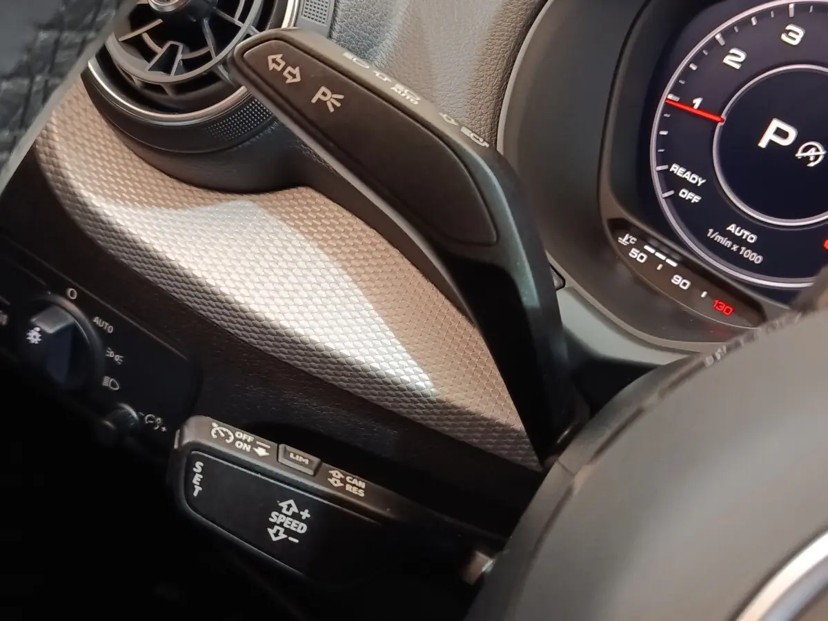 Détail intérieur côté gauche de l’Audi Q2 gris foncé 2022, avec commandes au volant et tableau de bord digital.