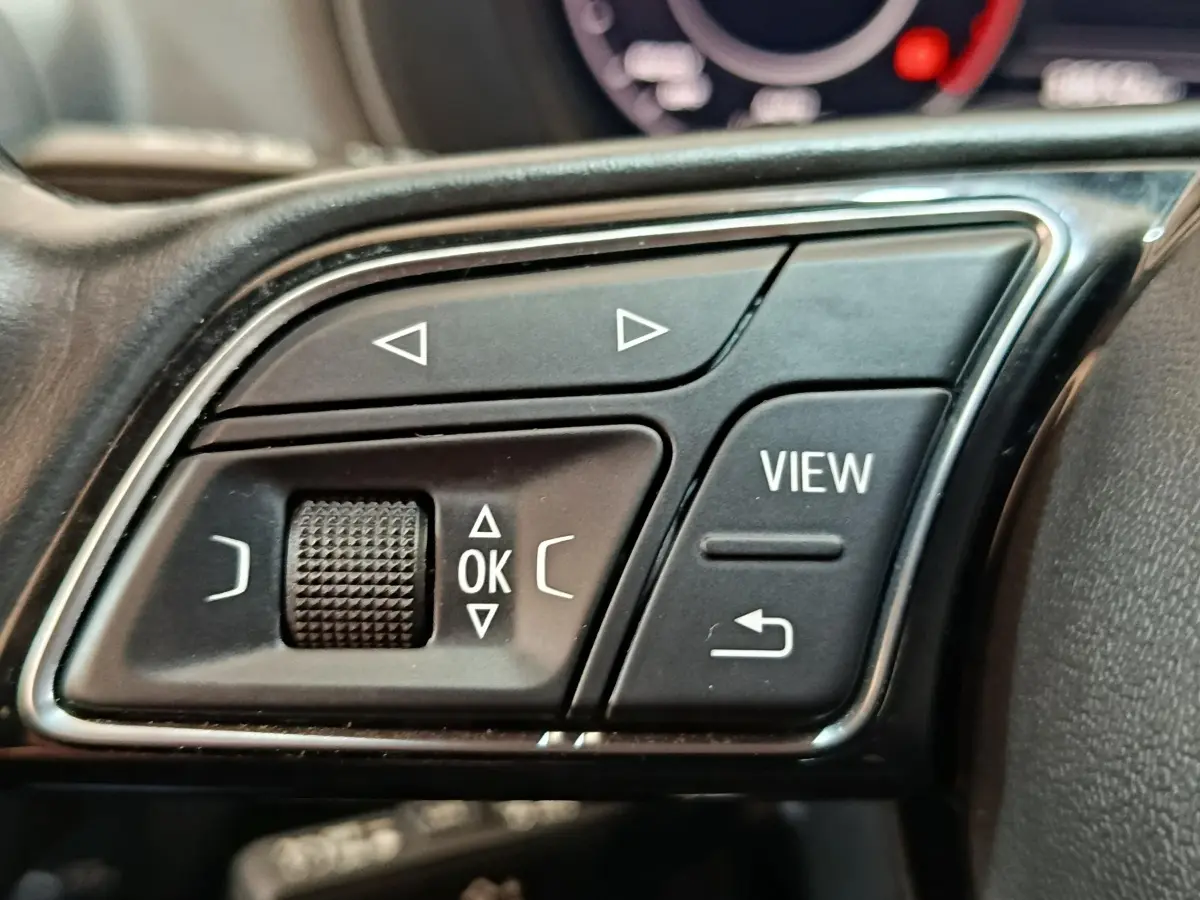 Gros plan sur les commandes multifonctions en plastique noir du volant d’un Audi Q2 35 TFSI gris foncé, 2022.