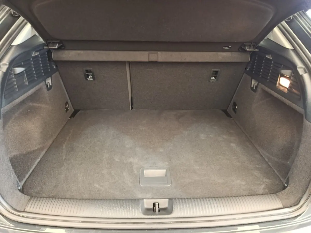 Vue intérieure du coffre spacieux et propre de l'Audi Q2 gris foncé, avec banquette arrière rabattable visible.