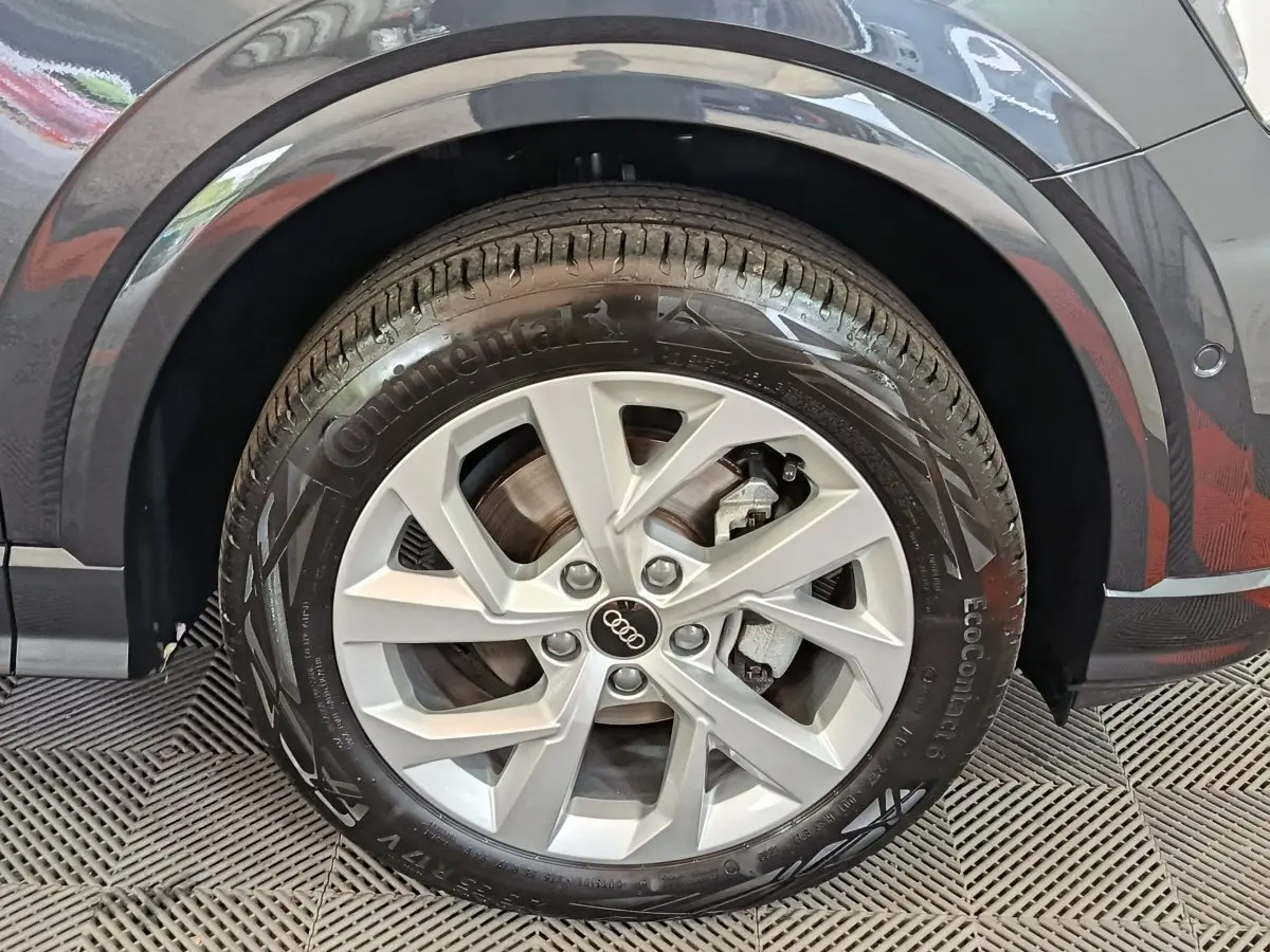 Gros plan sur la roue avant droite d’un Audi Q2 gris foncé, avec jante en alliage et pneu Continental.