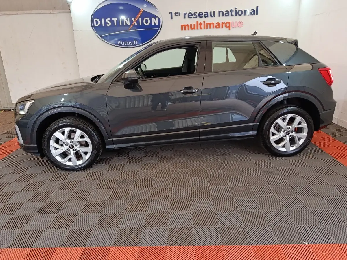 Audi Q2 gris foncé vue de profil côté gauche, avec jantes argentées et rétroviseurs assortis.