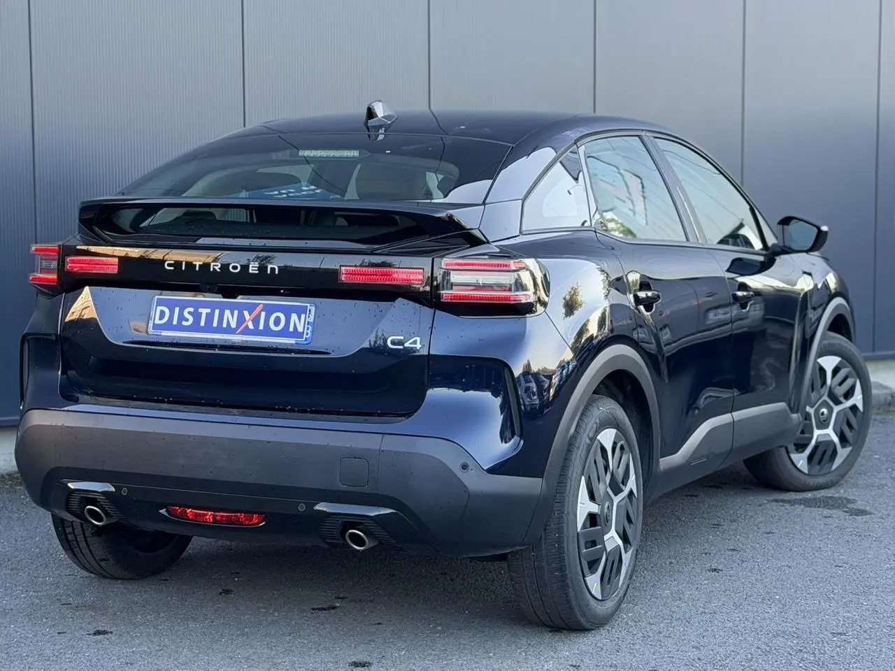 Vue 3/4 arrière droite d'une Citroën C4 Hybrid 145 bleu Eclipse avec feux arrière LED et double sortie d'échappement.