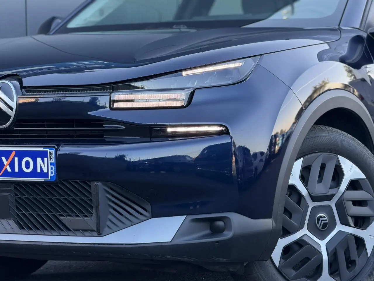 Vue 3/4 avant droit d'une Citroën C4 Hybrid 145 bleu Eclipse avec phares LED et jante au design moderne.